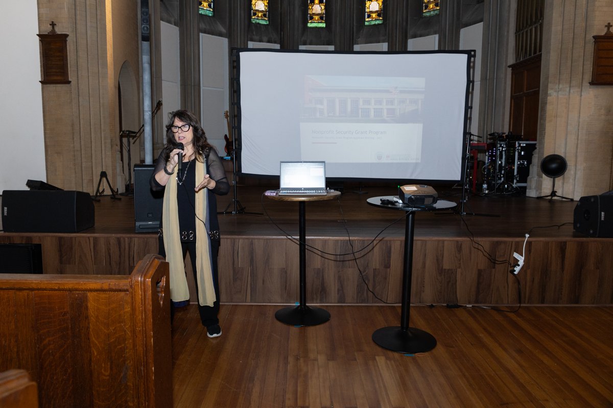 Sharon Daugherty presenting on stage with a microphone